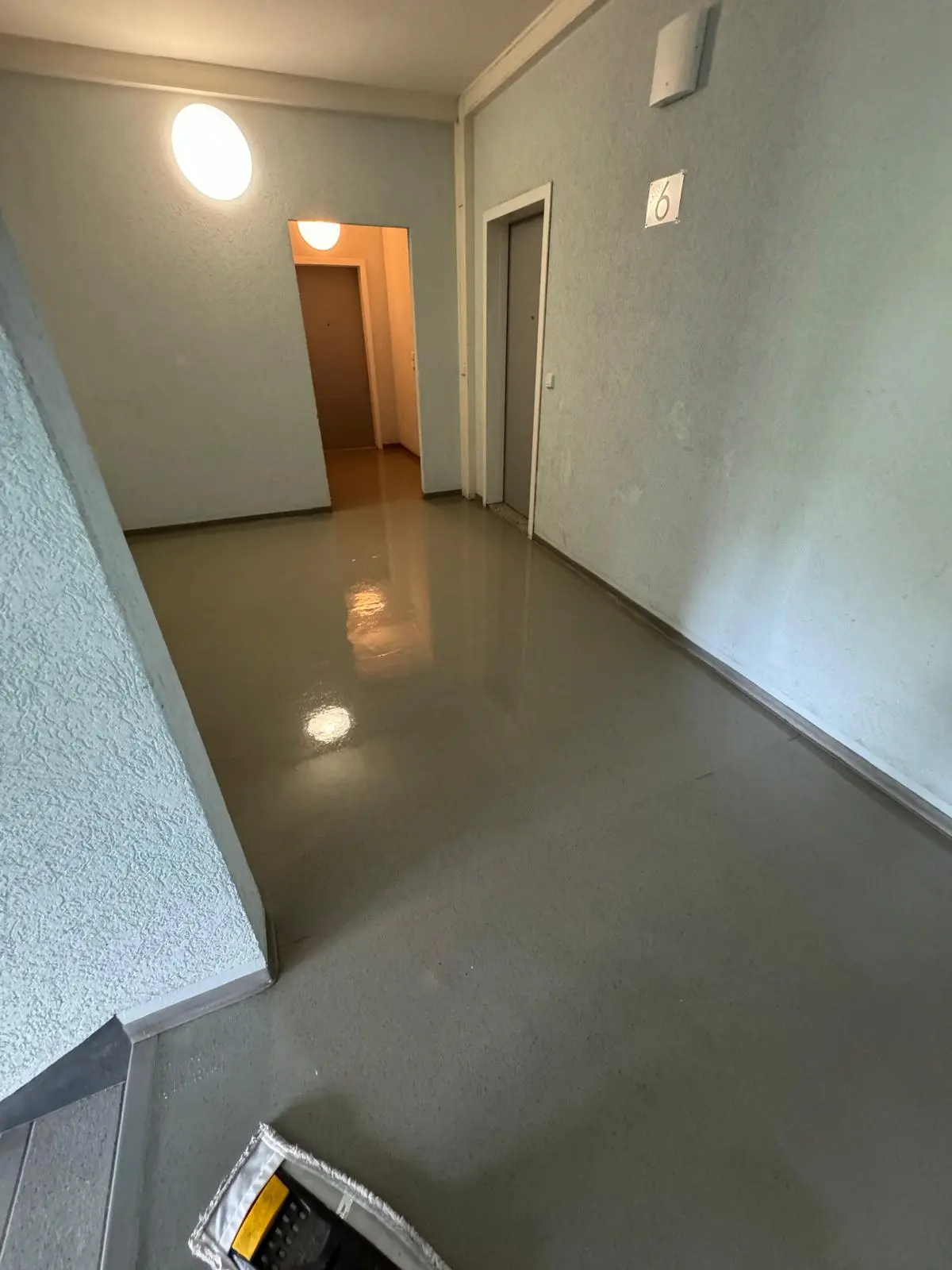 SCHWAMM-SERVICE GmbH, Arbeiter beim Reinigen des Büros, Achtung nasser Boden, Schild